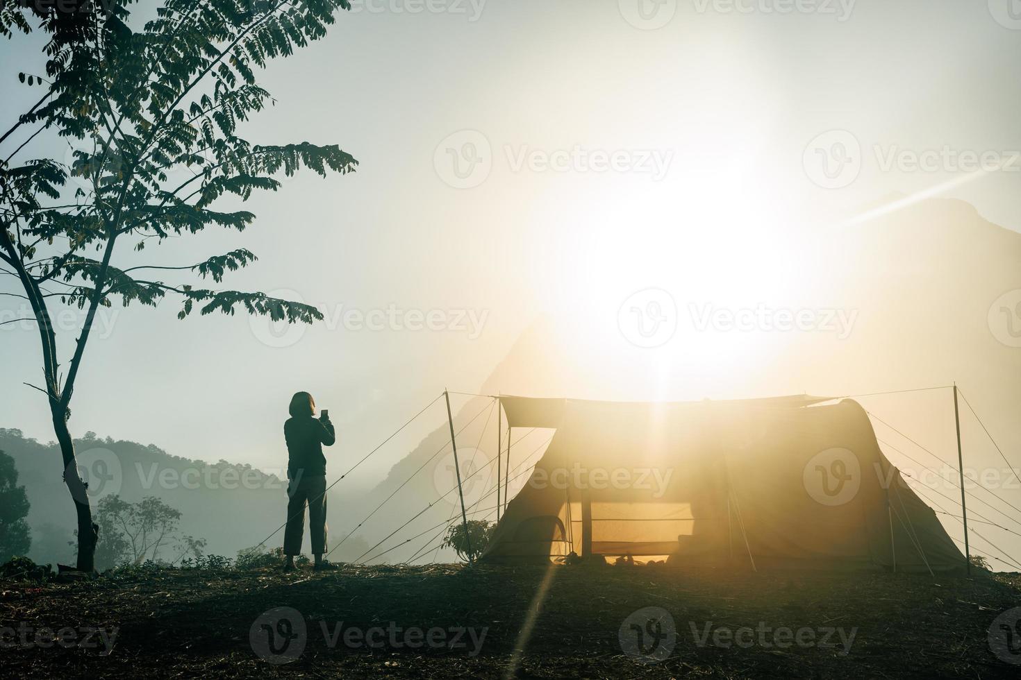 jeune femme avec tente le matin devant les montagnes avec nuage dans le parc naturel, concept de tourisme photo