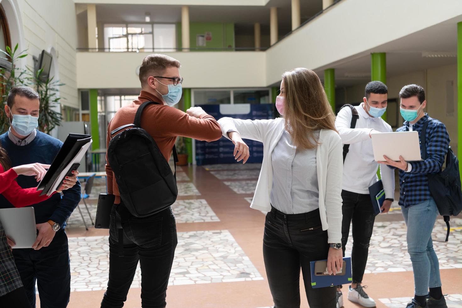 les étudiants saluent une nouvelle poignée de main normale contre le coronavirus et se cognent le coude photo