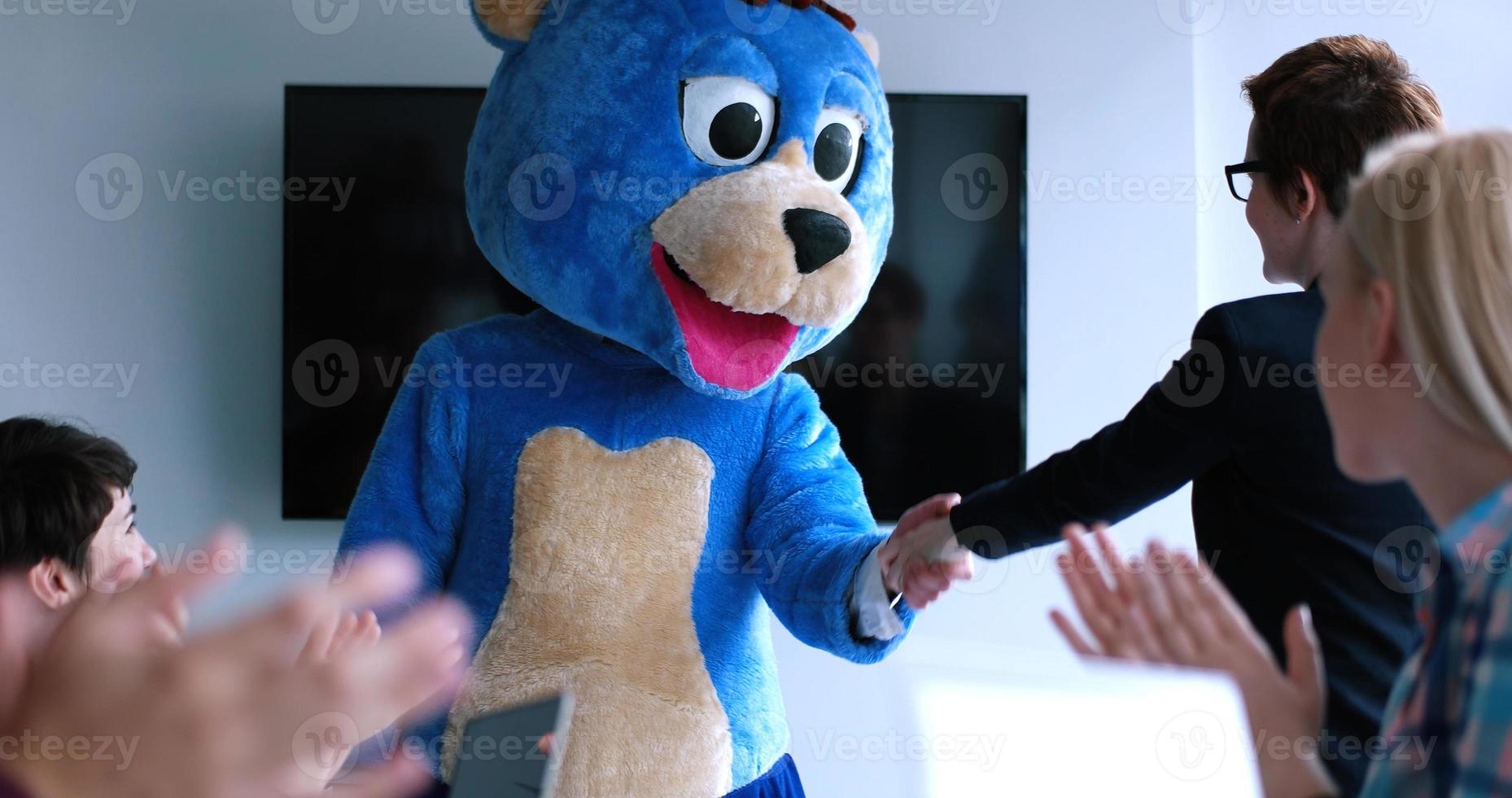 patron habillé en ours s'amusant avec des gens d'affaires dans un bureau branché photo