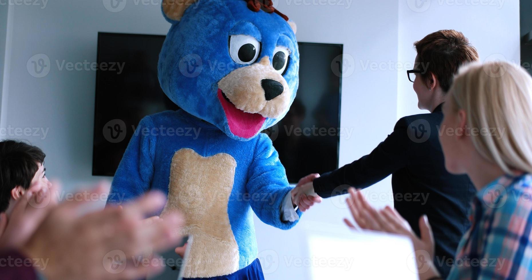 patron habillé en ours s'amusant avec des gens d'affaires dans un bureau branché photo