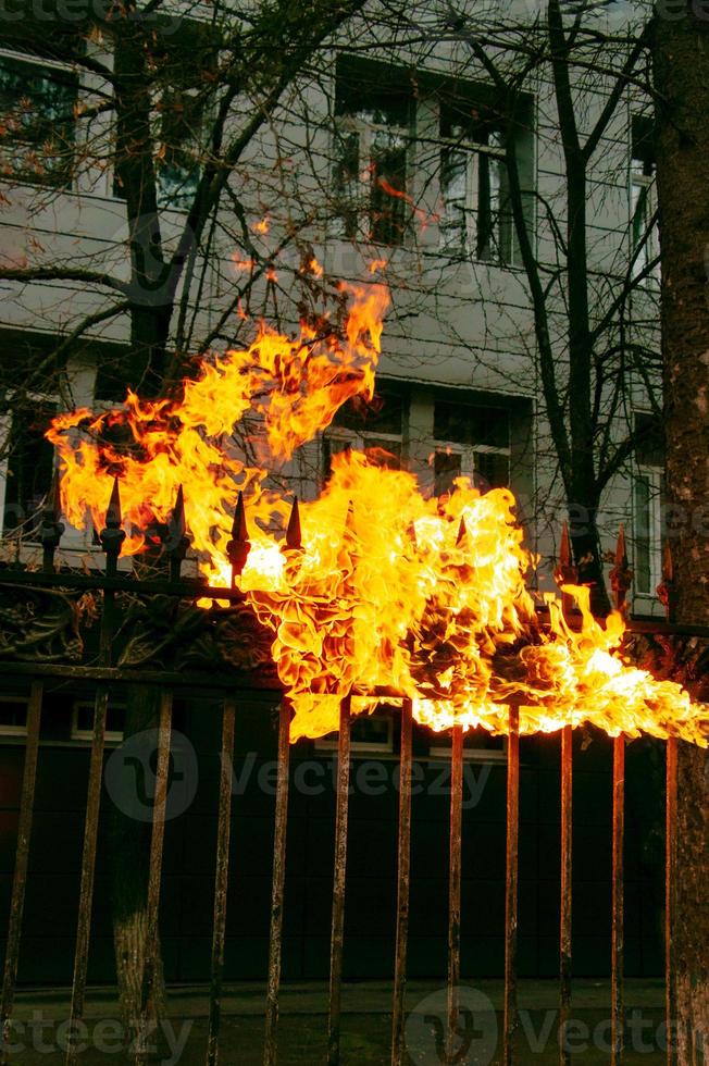 clôture métallique en feu. le processus de combustion de la vieille peinture sur une structure métallique à l'aide d'un brûleur à gaz photo