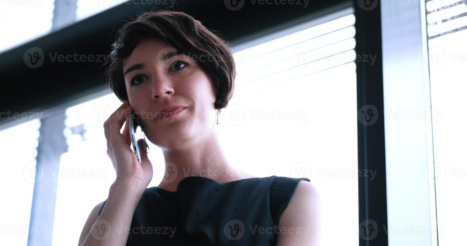 fille d'affaires debout dans un immeuble moderne près de la fenêtre avec téléphone photo