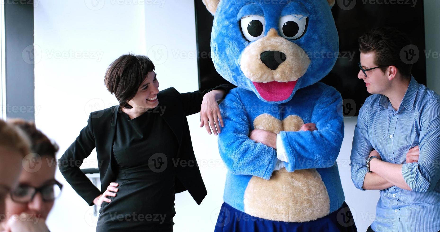 patron habillé en ours s'amusant avec des gens d'affaires dans un bureau branché photo