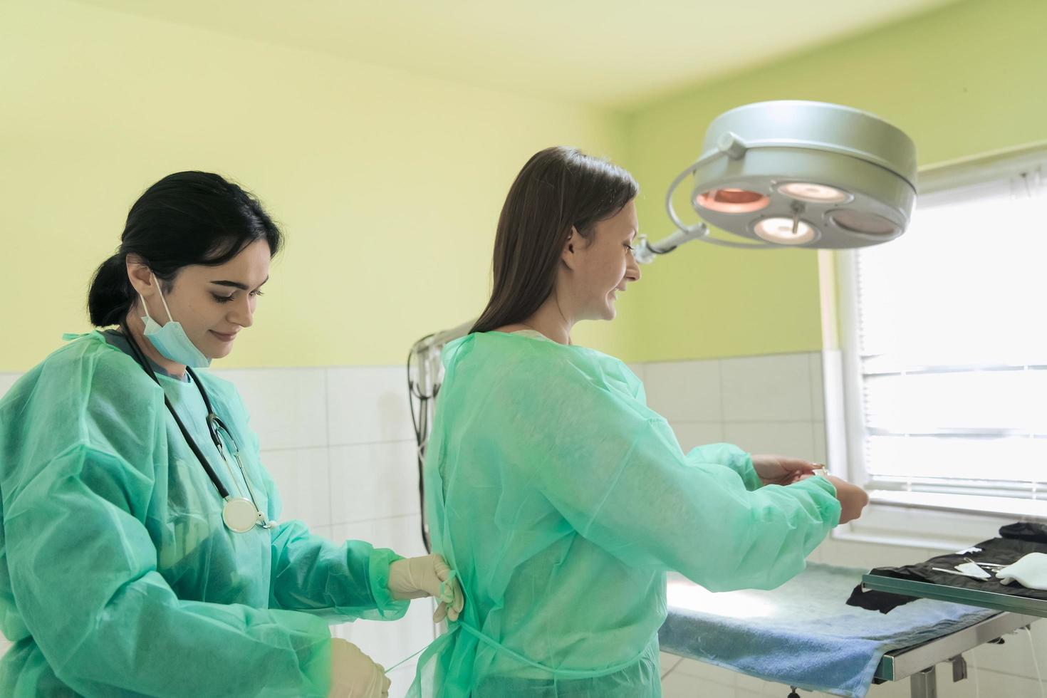 la femme chirurgienne ou vétérinaire des animaux met un masque médical. le médecin se prépare à la chirurgie dans la salle d'opération. médecine et soins de santé photo