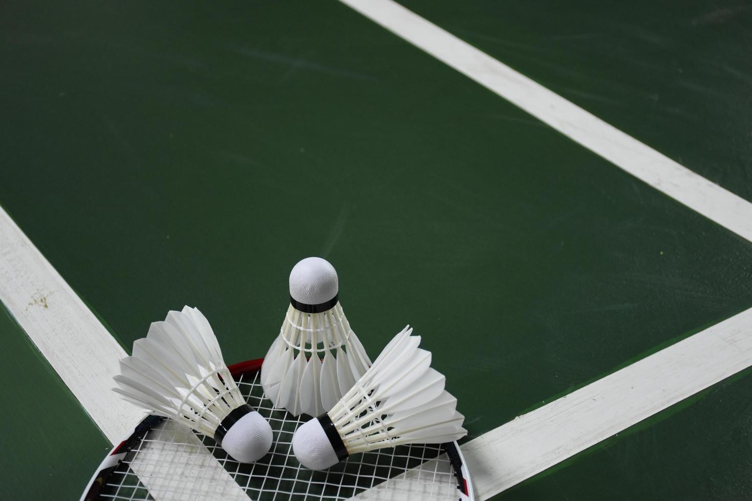 Volants et raquettes de badminton blanc crème sur sol vert dans un terrain de badminton intérieur photo