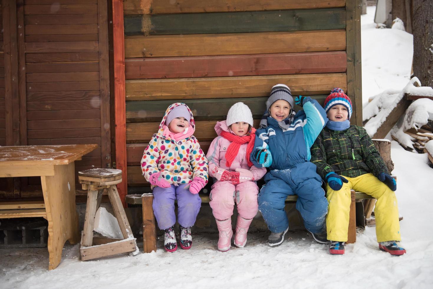 petit groupe d'enfants assis devant une cabane en bois photo