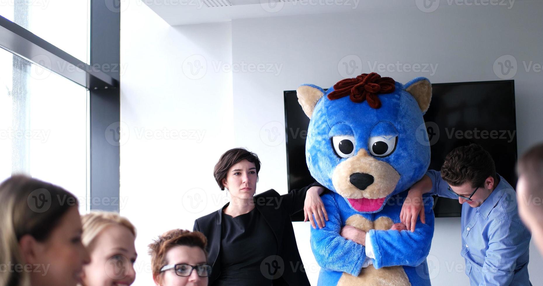 patron habillé en ours s'amusant avec des gens d'affaires dans un bureau branché photo