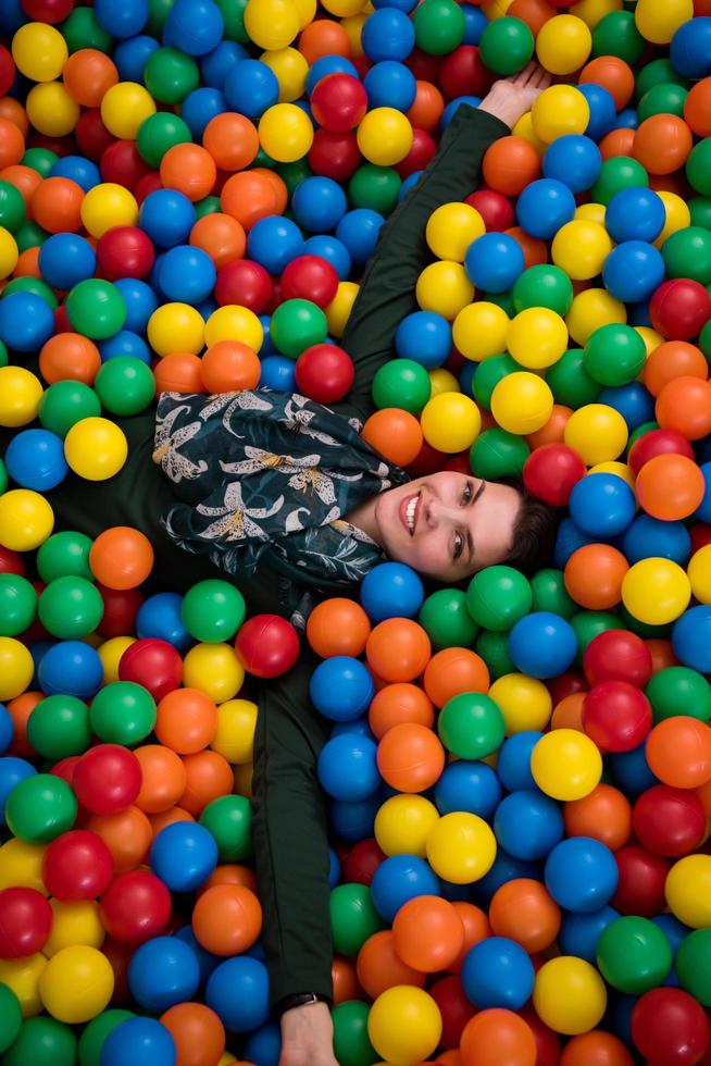 jeune maman jouant avec des enfants dans la piscine avec des boules colorées photo