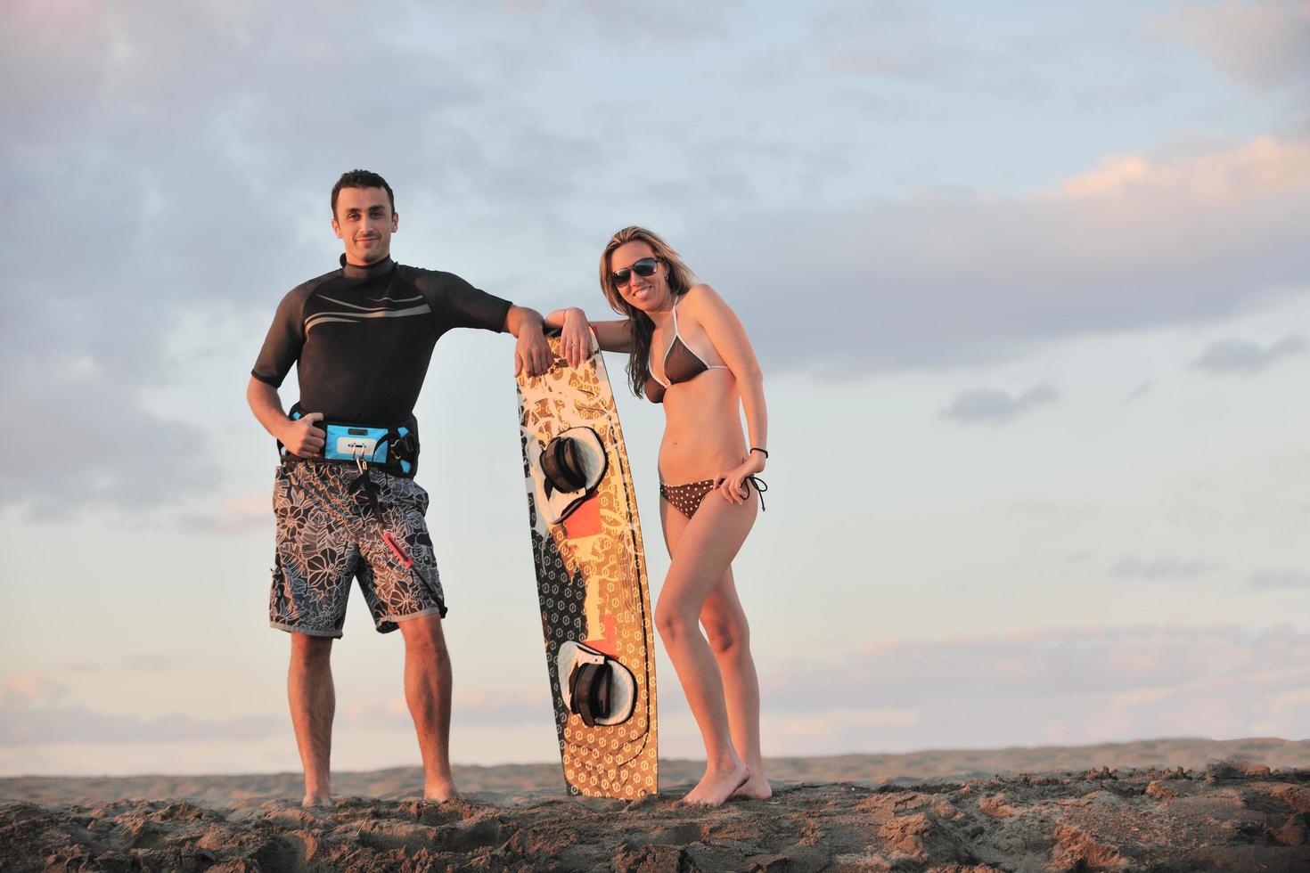 couple de surf posant sur la plage au coucher du soleil photo