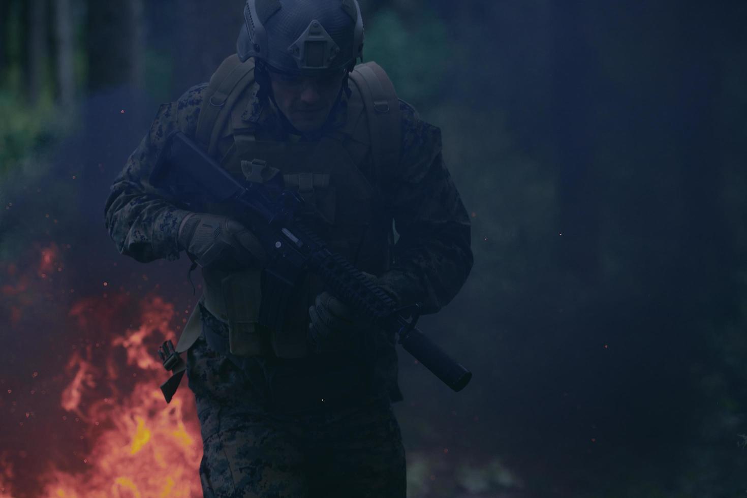 soldat en action la nuit sautant par-dessus le feu photo