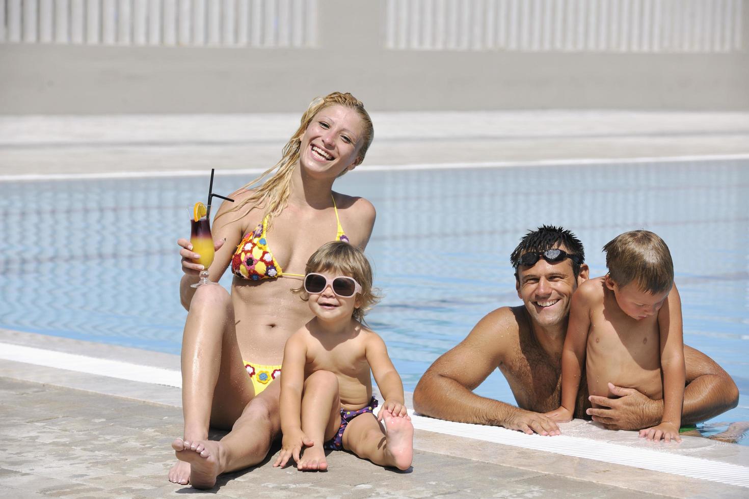 une jeune famille heureuse s'amuse à la piscine photo