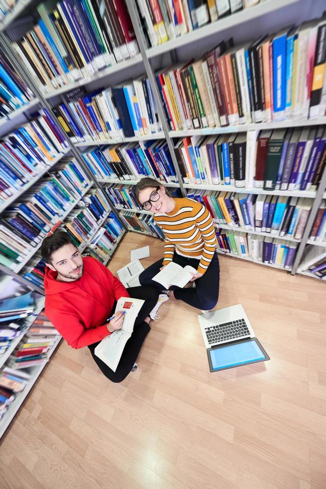 les élèves utilisent un cahier, un ordinateur portable et une bibliothèque scolaire photo