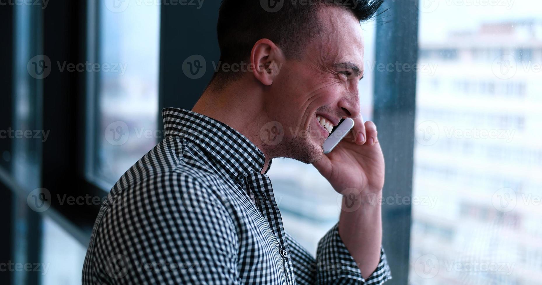 homme d'affaires parlant au téléphone portable, regardant par la fenêtre du bureau photo