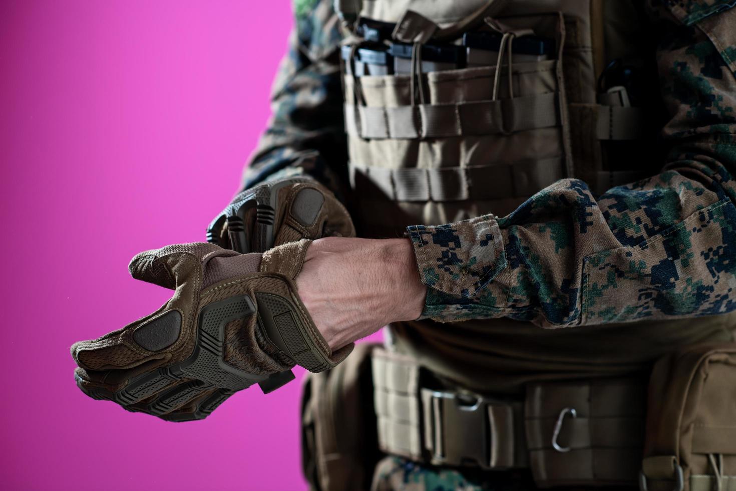 gros plan des mains du soldat mettant des gants de protection sur fond rose photo