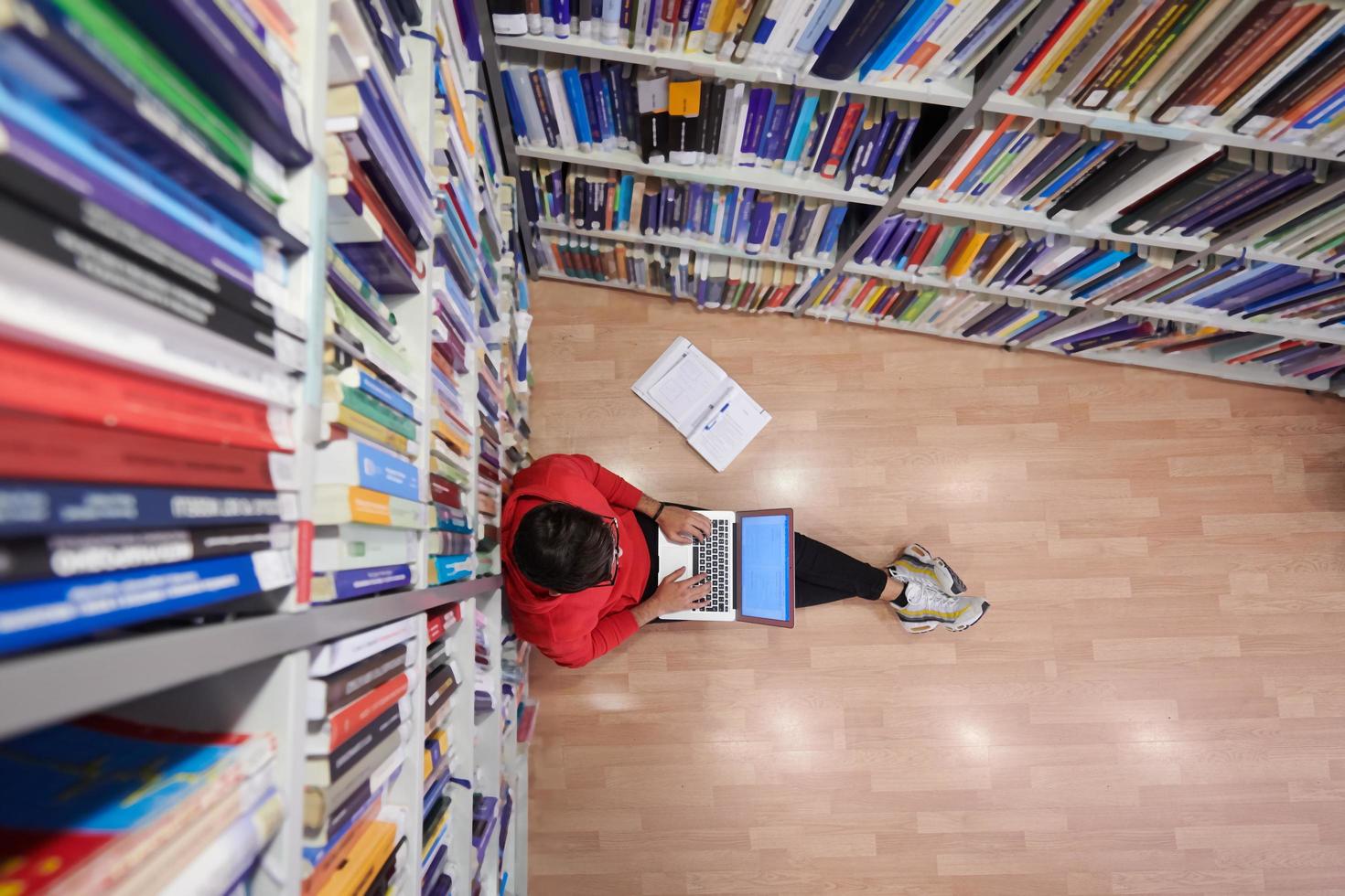 les élèves utilisent un cahier, un ordinateur portable et une bibliothèque scolaire photo