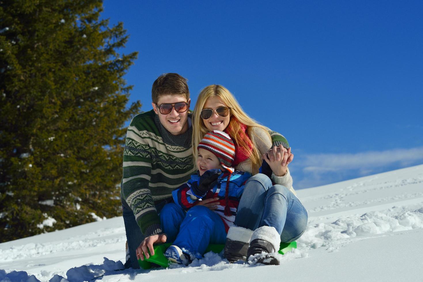 famille s'amusant sur la neige fraîche en hiver photo