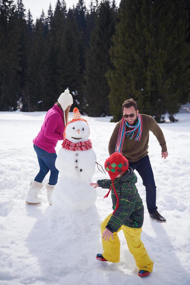 famille heureuse construisant un bonhomme de neige photo