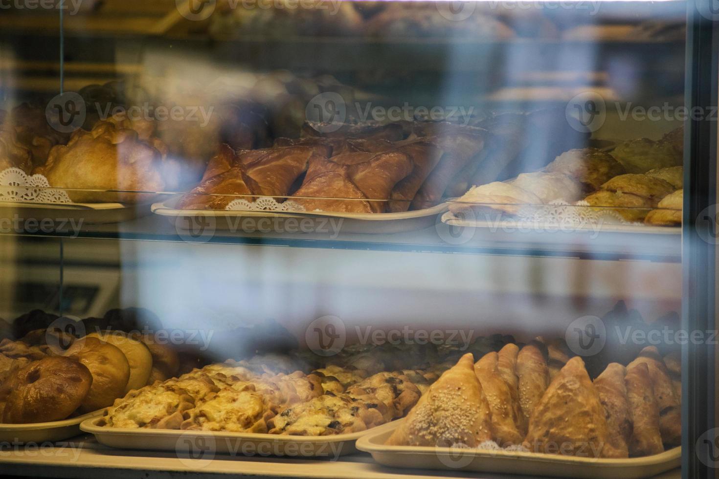 une riche variété de tartes aux brioches, beignets dans une vitrine de confiserie typique. petits pains cuits à la boulangerie. gros plan de nourriture de dessert sucré. photo