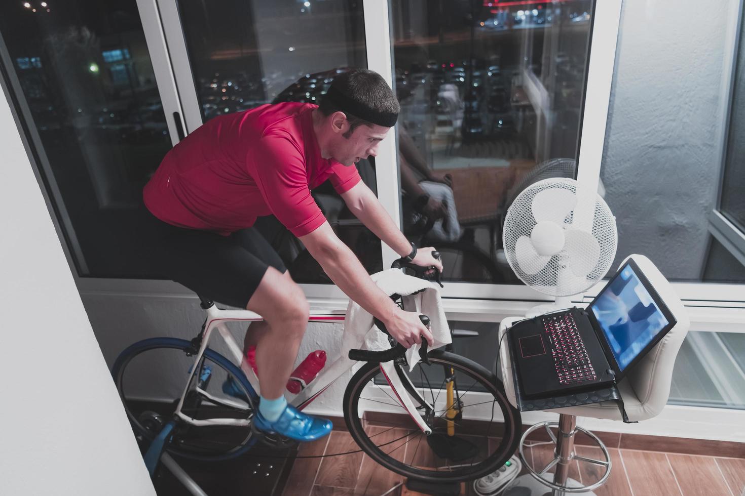 homme faisant du vélo sur l'entraîneur de la machine il s'exerce à la maison la nuit en jouant au jeu de course de vélo en ligne photo