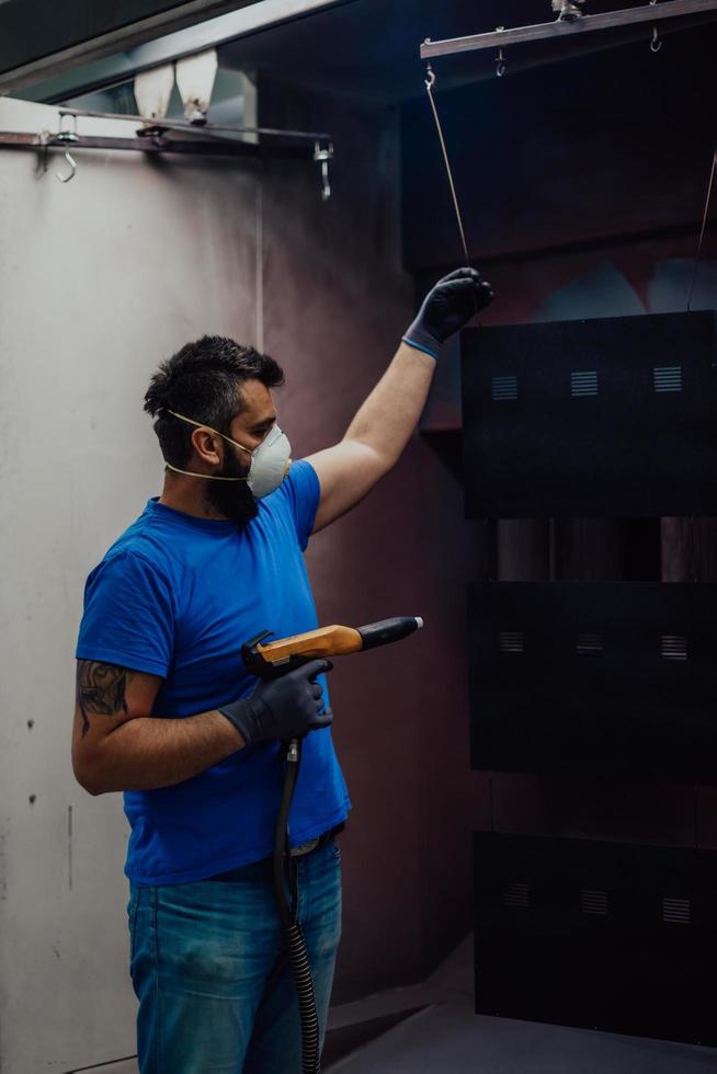 le peintre peint l'élément de fer. pièces de peinture industrielle. dessins en métal photo