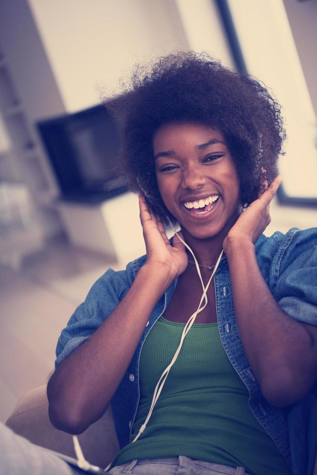 femme afro-américaine à la maison dans une chaise avec tablette et casque photo