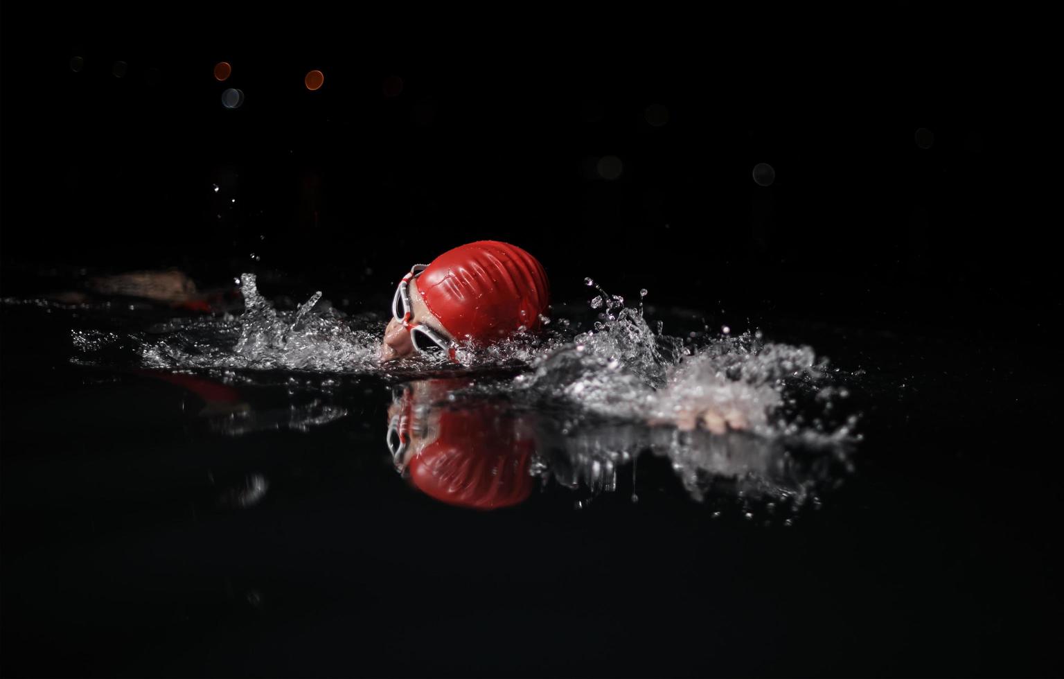 athlète de triathlon nageant dans la nuit noire portant une combinaison de plongée photo