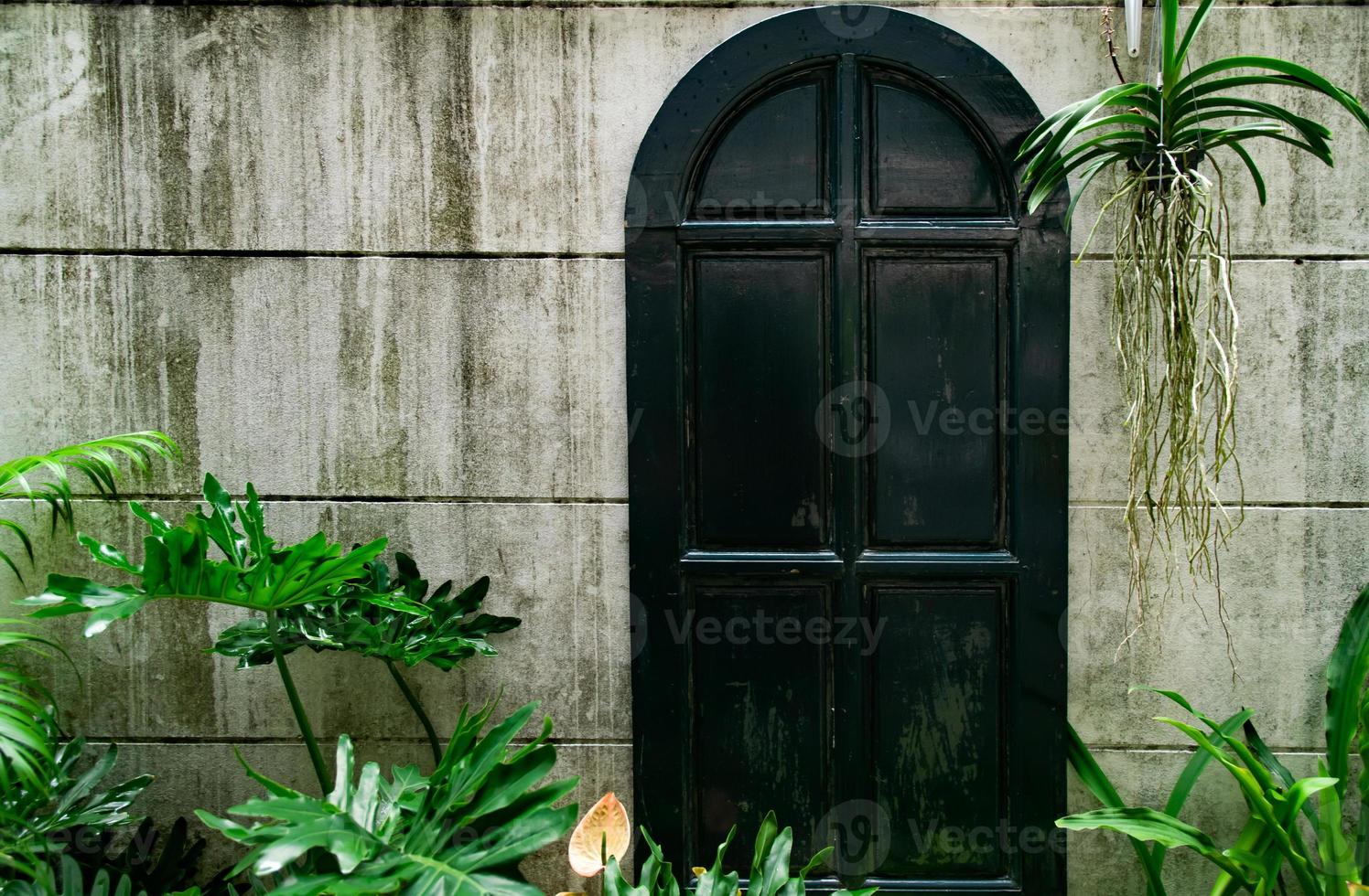 mur de jardin et porte antique, l'entrée est pleine de plantes, se sentir au milieu de la nature dans la forêt tropicale, concept de thérapie de la nature. photo