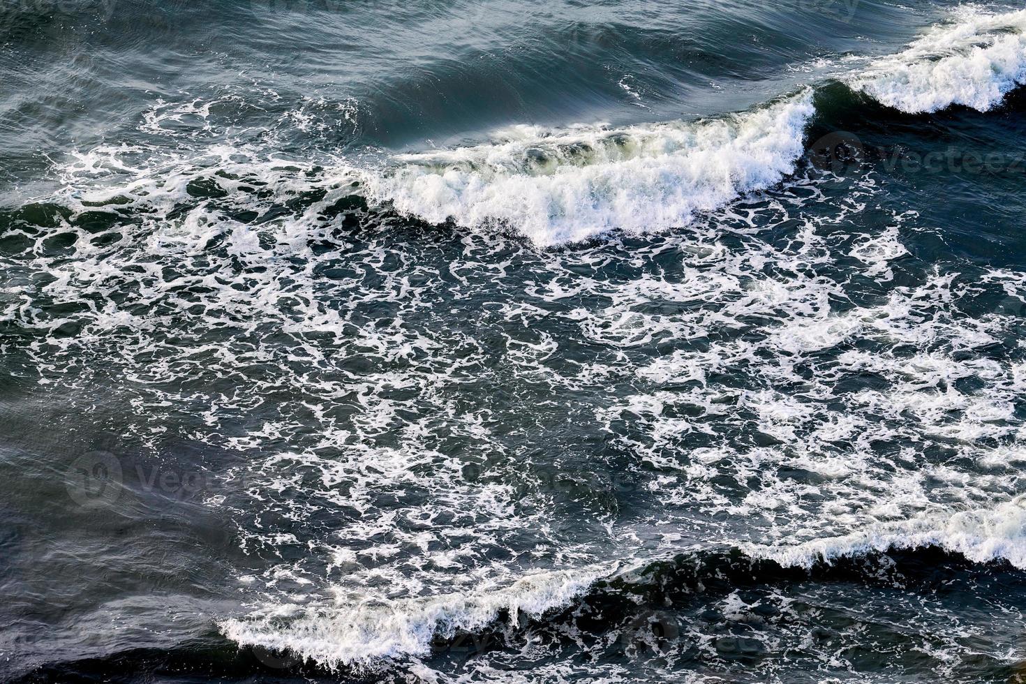 eaux de mer d'un bleu profond éclaboussant de vagues mousseuses, surface de l'eau de l'océan ondulé bleu foncé, mer orageuse photo