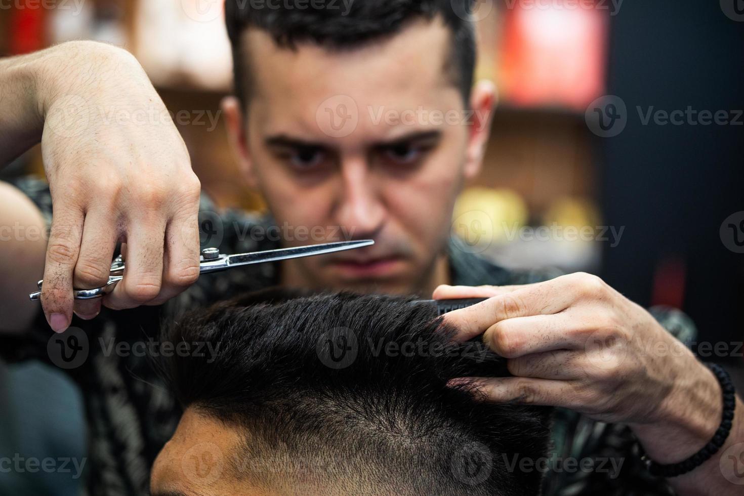 salon de coiffure. gros plan sur la coupe de cheveux de l'homme, le maître fait la coiffure dans le salon de coiffure. gros plan, le maître barbier fait la coiffure et le style avec des ciseaux. concept salon de coiffure. photo