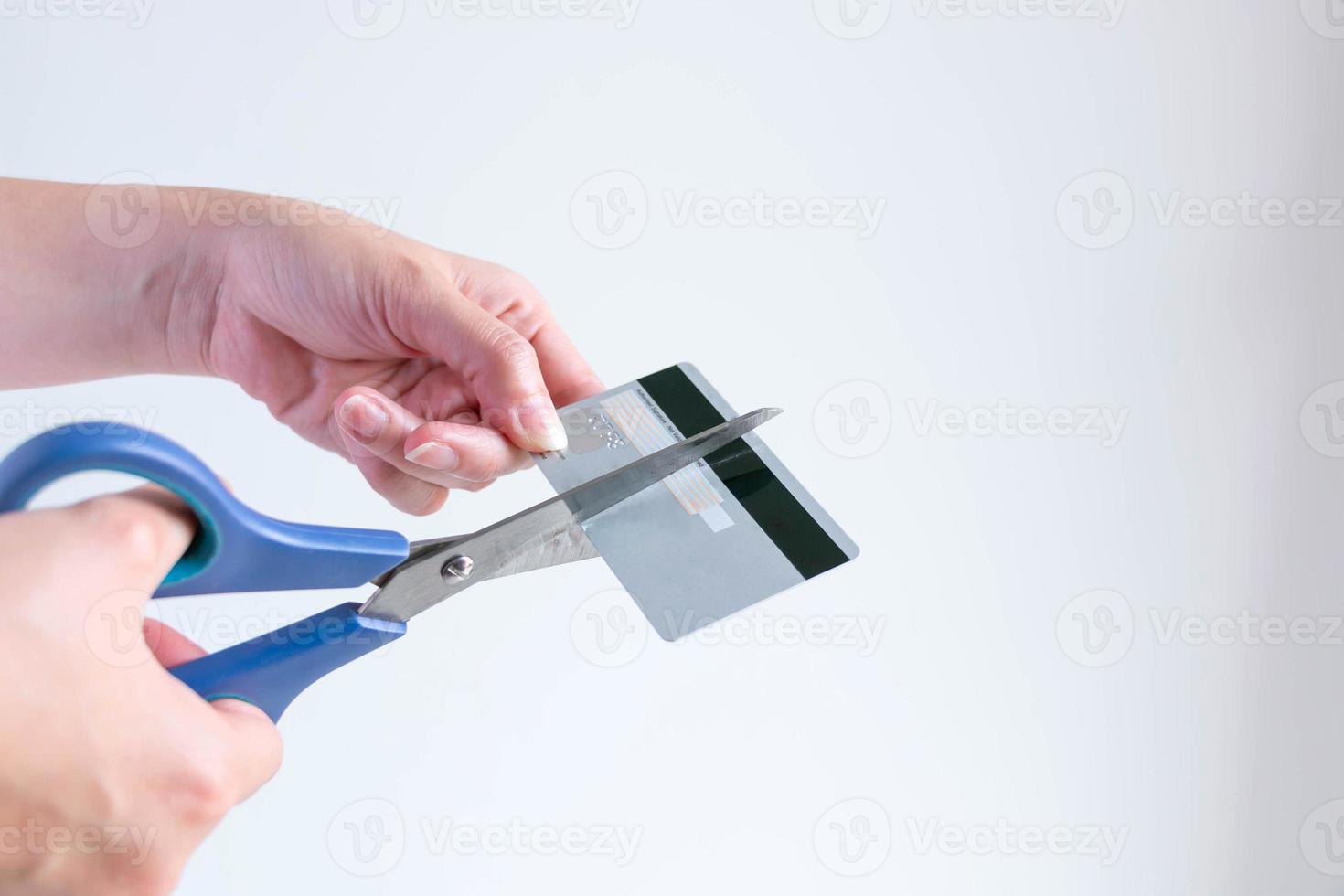 une femme coupant une carte de crédit avec des ciseaux pour arrêter de s'endetter. photo