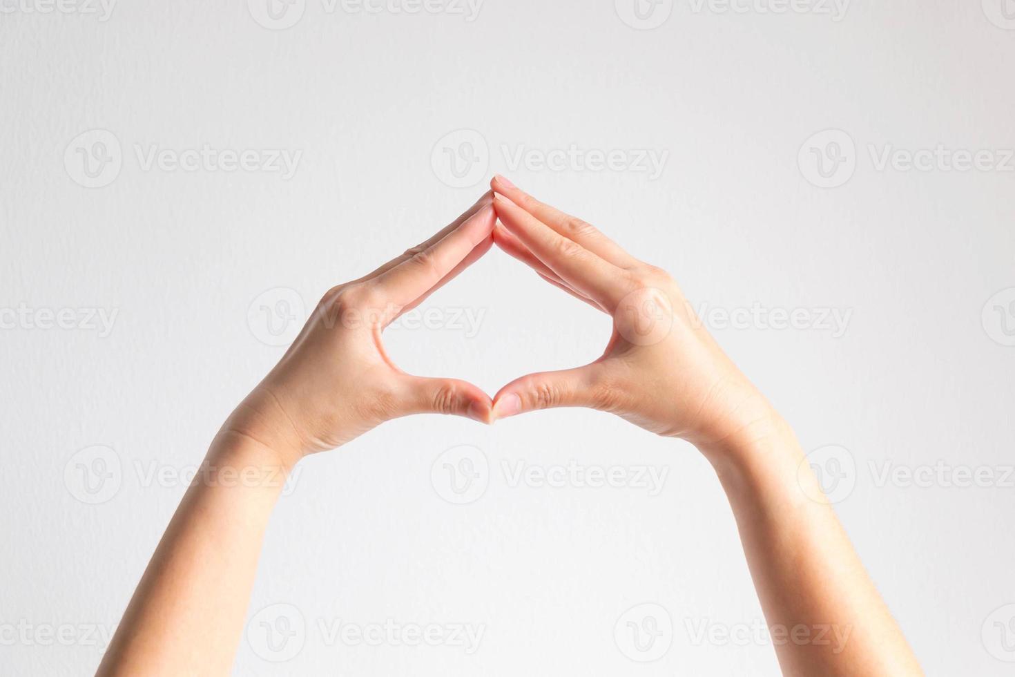 les mains posent le bout des doigts épissé pour être un cadre en forme de bêche sur fond blanc. photo