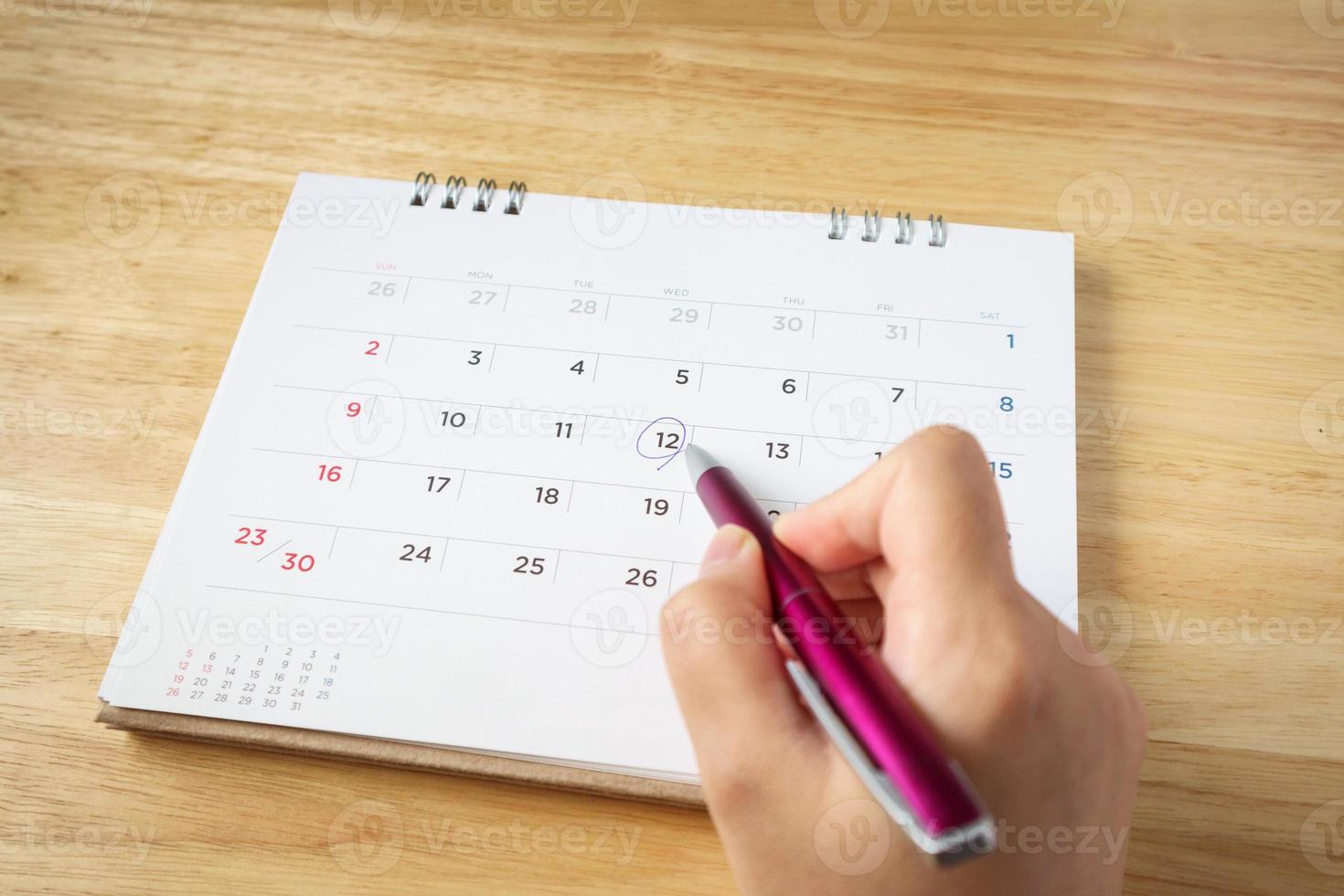 page de calendrier sur la table avec une main féminine tenant un stylo, vue de dessus photo