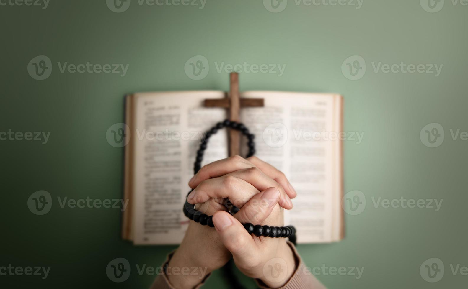 concept de spiritualité, de religion et d'espoir. personne priant par la sainte bible et croix sur le bureau. symbole d'humilité, de supplication, de croyance et de foi pour le peuple chrétien. vue de dessus photo