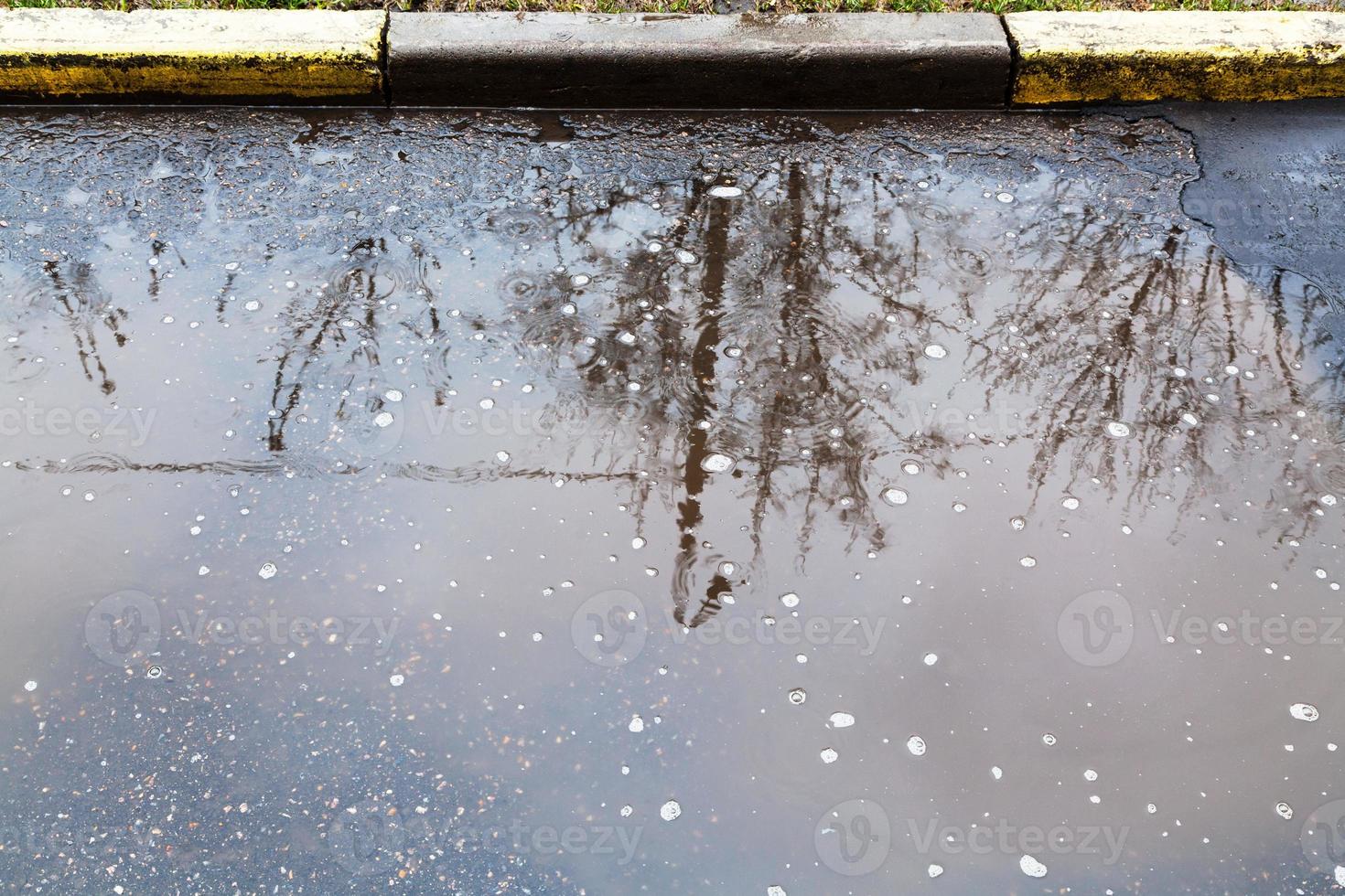 flaque d'eau sur la rue urbaine en jour de pluie photo