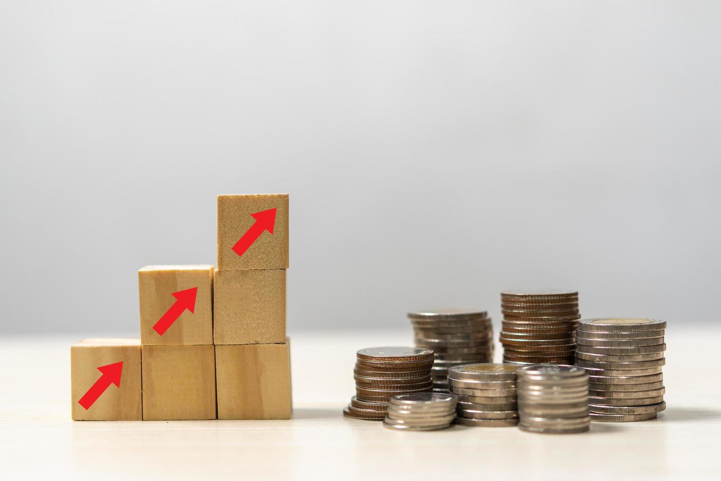 investissements en finance d'entreprise économie pile inflation des pièces et flèche rouge avec cube de bois sur le bureau. photo