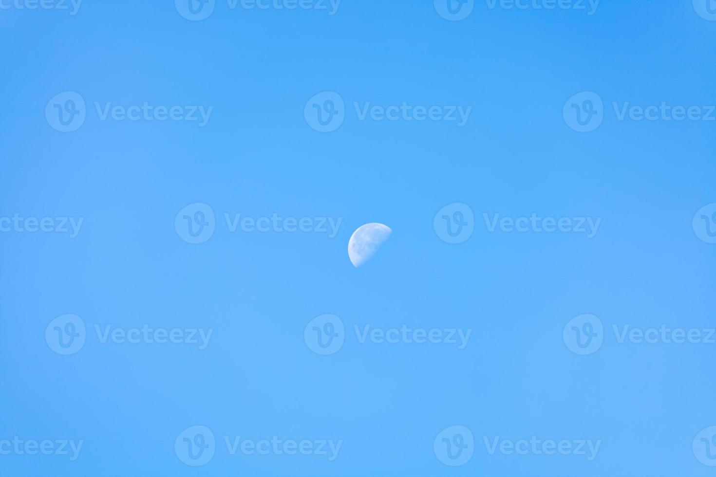 moitié de lune dans le ciel bleu clair du matin photo