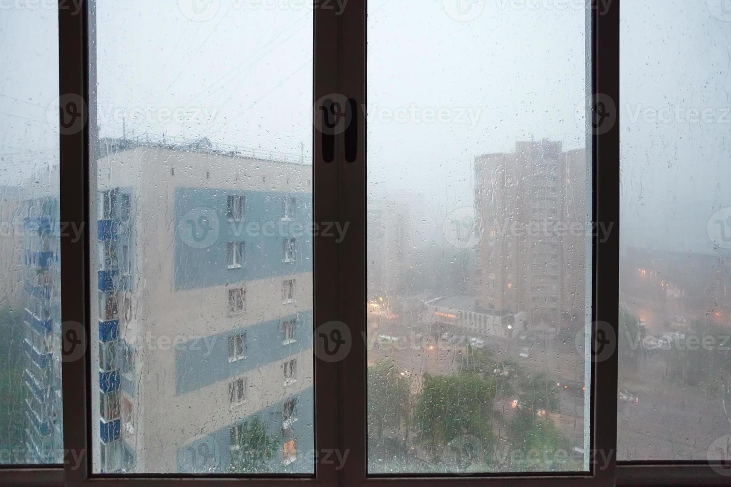 gouttes de pluie sur la fenêtre de la maison urbaine pendant la pluie photo