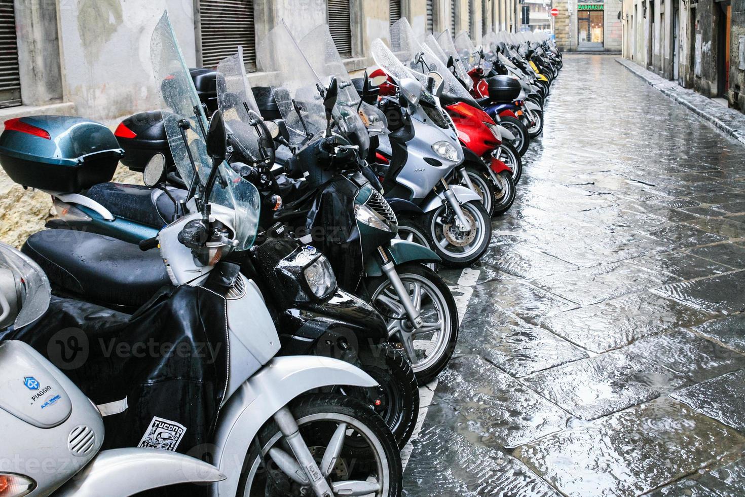 De nombreux scooters mouillés garés dans la rue à Florence photo