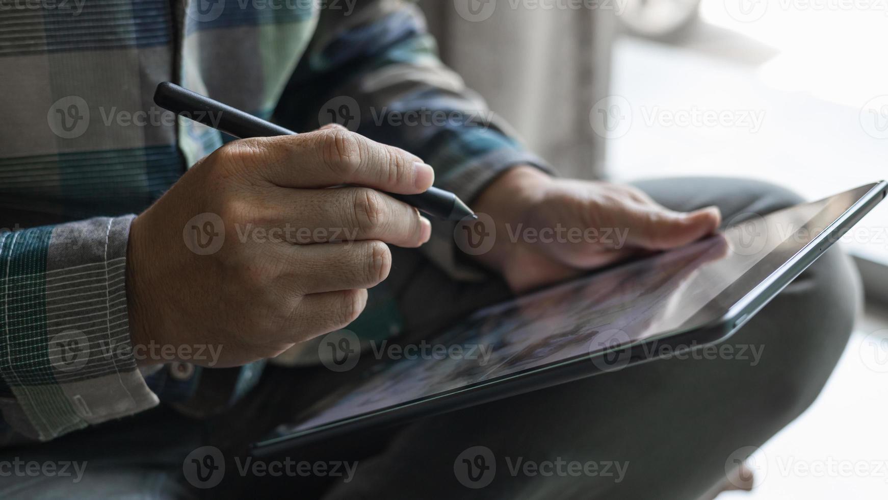 les concepteurs choisissent des pièces de décoration pour la maison sur une tablette, un graphiste travaille sur la conception d'un stylo sur une tablette, un homme tenant un stylo et une tablette assis par terre dans la maison. photo