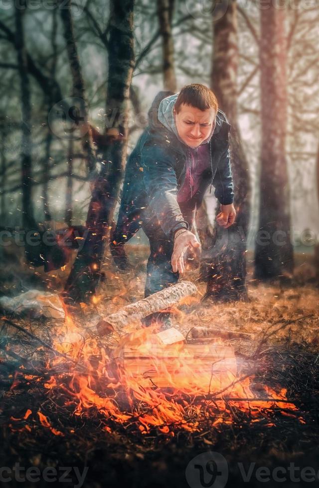 un homme allume un feu de joie dans les bois photo