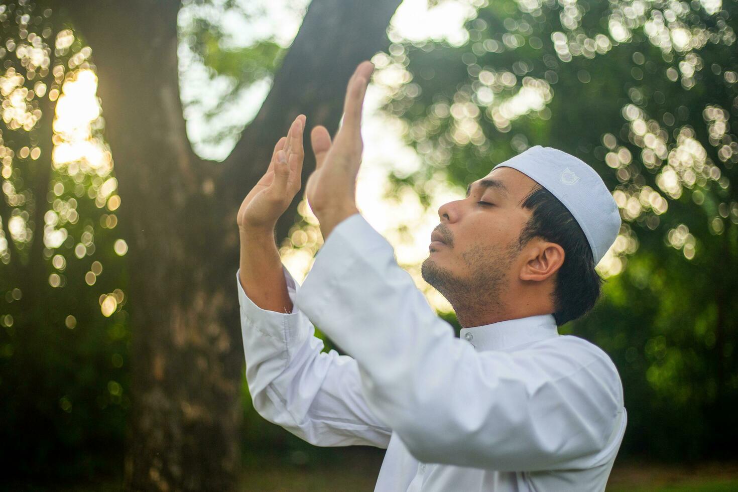 homme musulman asiatique priant allah dieu de l'islam tout en levant les bras, concept du festival du ramadan photo