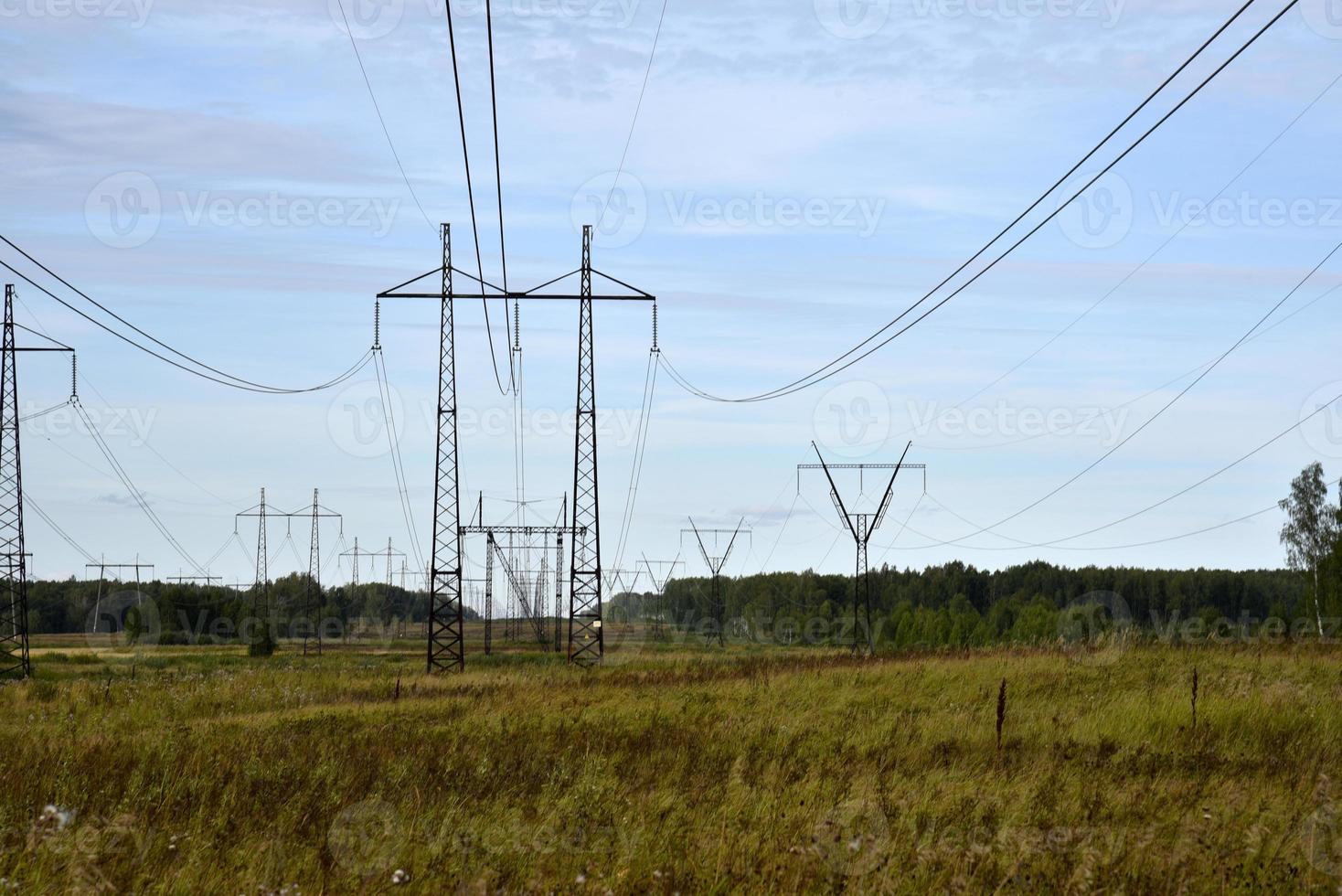 ligne électrique à haute tension sur le terrain un jour d'été. une ligne électrique dans un champ vert. photo