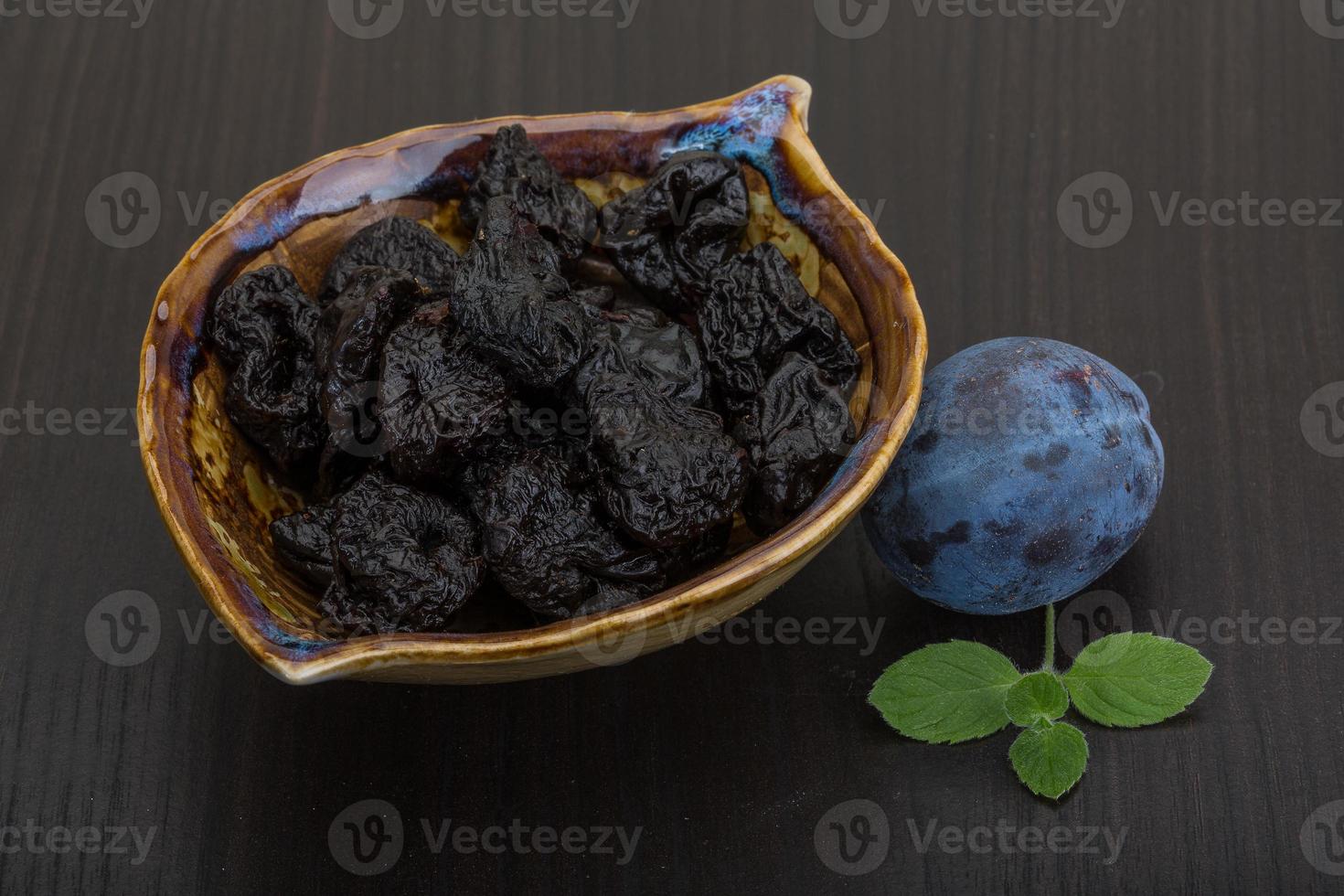 prunes séchées dans un bol sur fond de bois photo