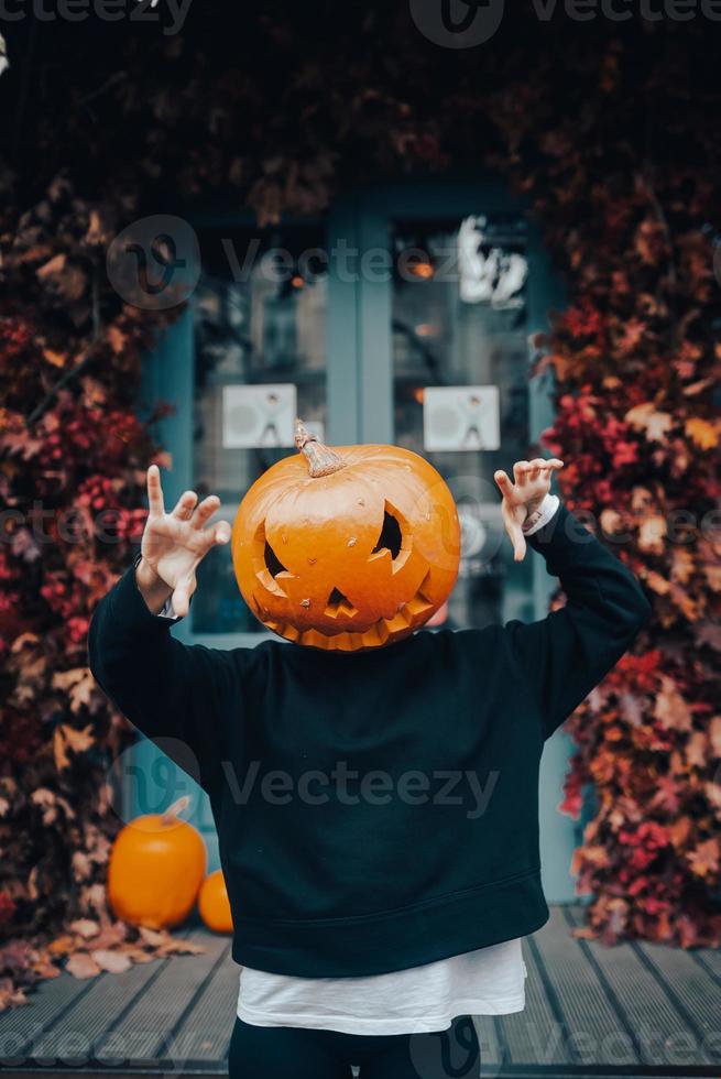 fille avec une tête de citrouille fait peur à la caméra photo