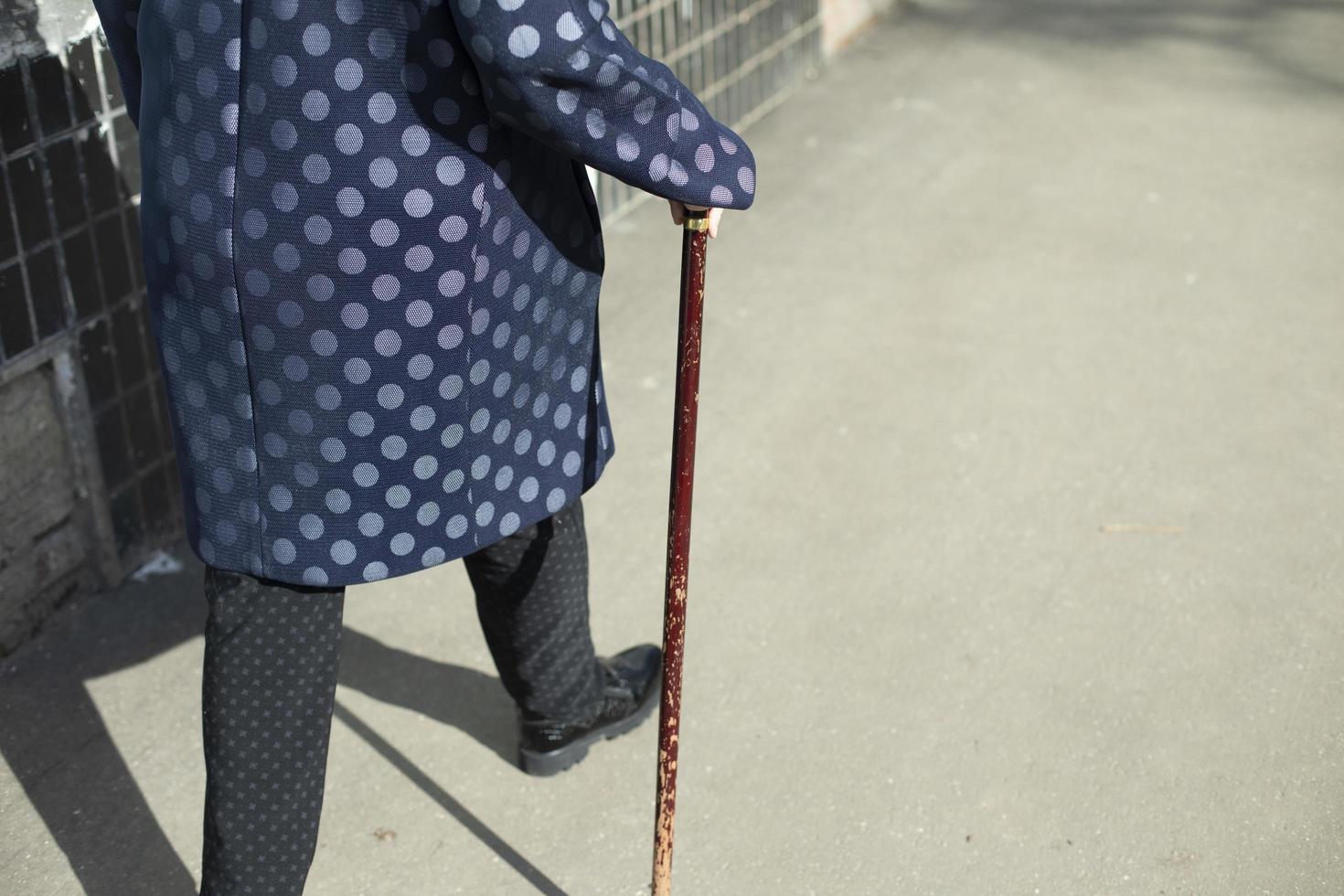 grand-mère avec canne. femme marche sur l'asphalte. photo