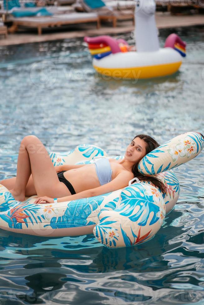 femme sur flamant gonflable flottant dans la piscine. photo