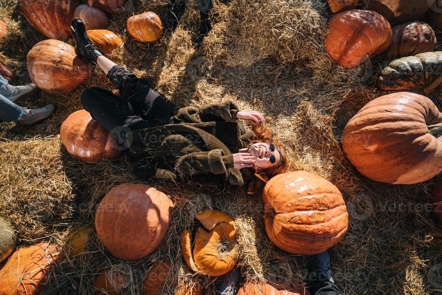 jeune fille allongée sur des meules de foin parmi les citrouilles. vue d'en-haut photo