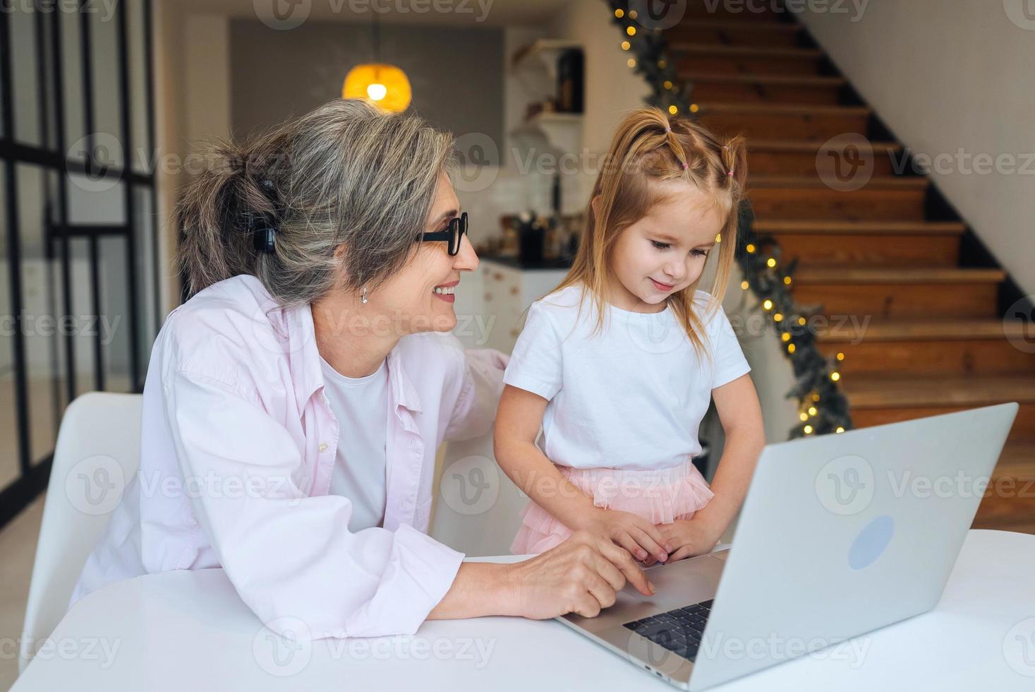 enfant et grand-mère regardant la caméra avec un ordinateur portable photo