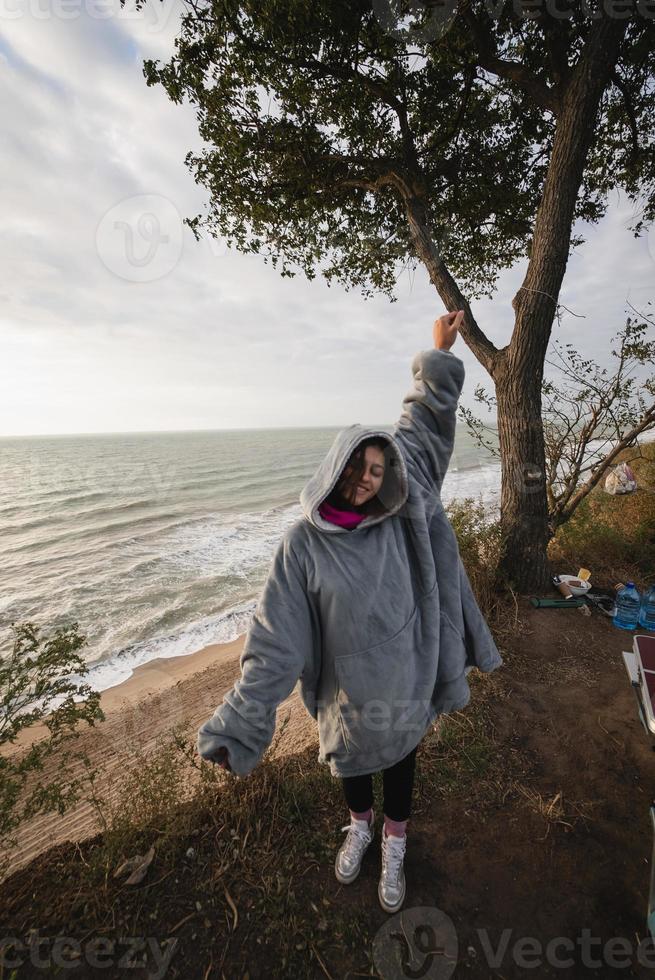 jeune femme sur le bord de mer d'automne froid se présentant à la caméra photo