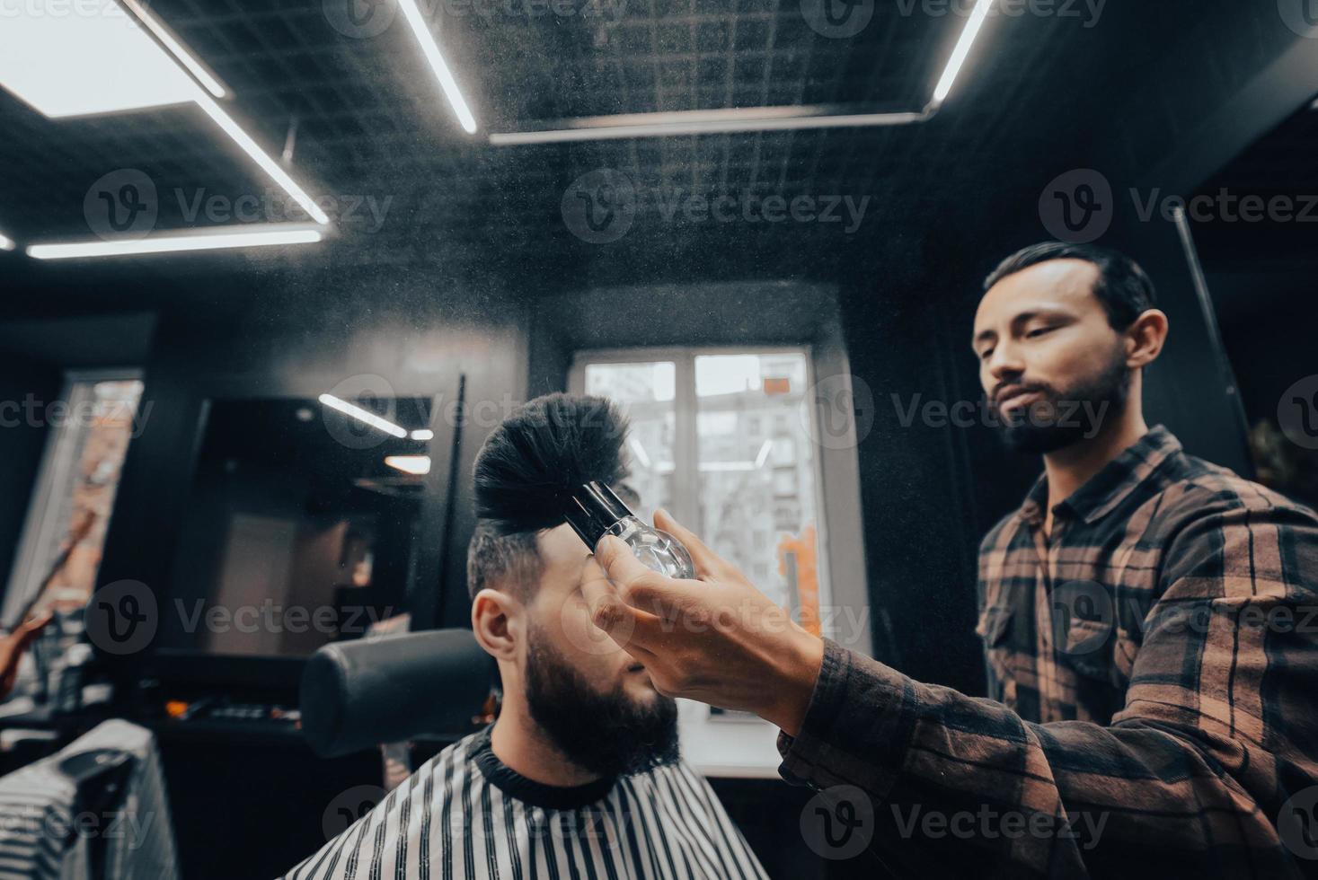 le maître enlève les cheveux restants du client avec une brosse photo